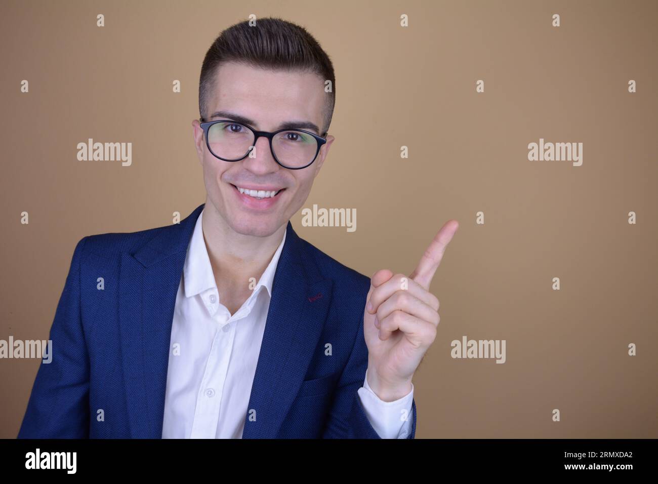 Sourire Jeune bel homme élégant pointant doigt sur le côté à Copy Space sur fond isolé Banque D'Images