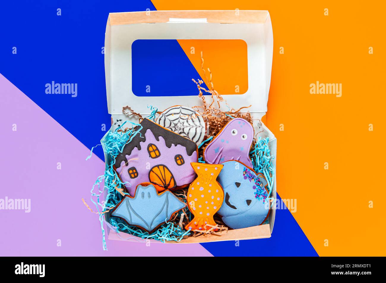 Biscuits de pain d'épice d'Halloween peints dans une boîte cadeau sur un fond géométrique lumineux. Banque D'Images