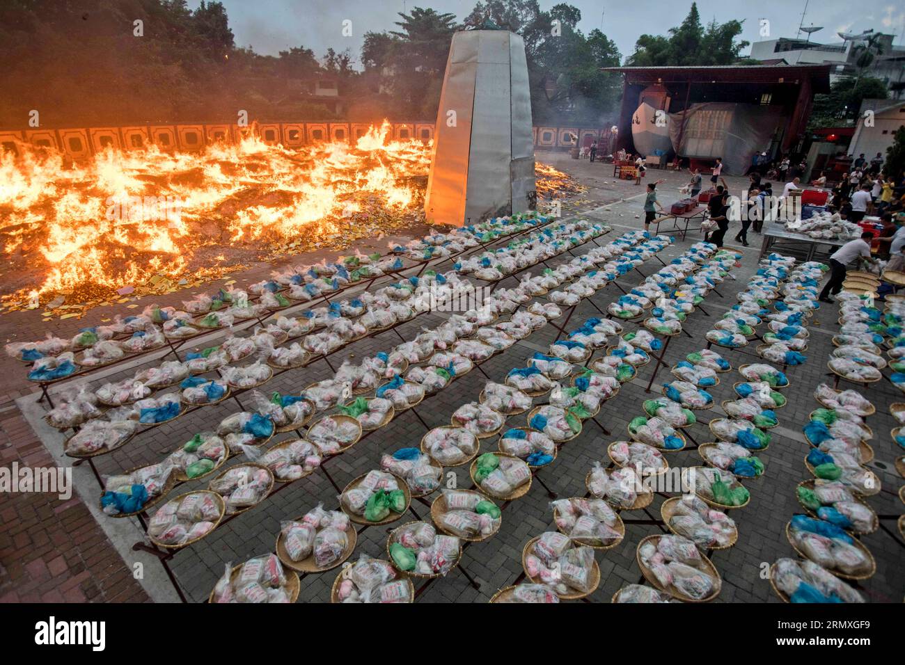 Ethnic Chinese people burn imitation money known as 'hell money' as they prepare offerings, during the Hungry Ghost Festival in Medan, North Sumatra, Indonesia, Wednesday, Aug. 30, 2023. The festival is celebrated during the seventh month of the Chinese lunar calendar, when prayers are offered to the dead and offerings of food and paper-made models of items such as televisions and cars are burned to appease wandering spirits as it is believed that the gates of hell are opened during the month and the souls of dead ancestors return to visit their relatives. (AP Photo/Binsar Bakkara) Banque D'Images
