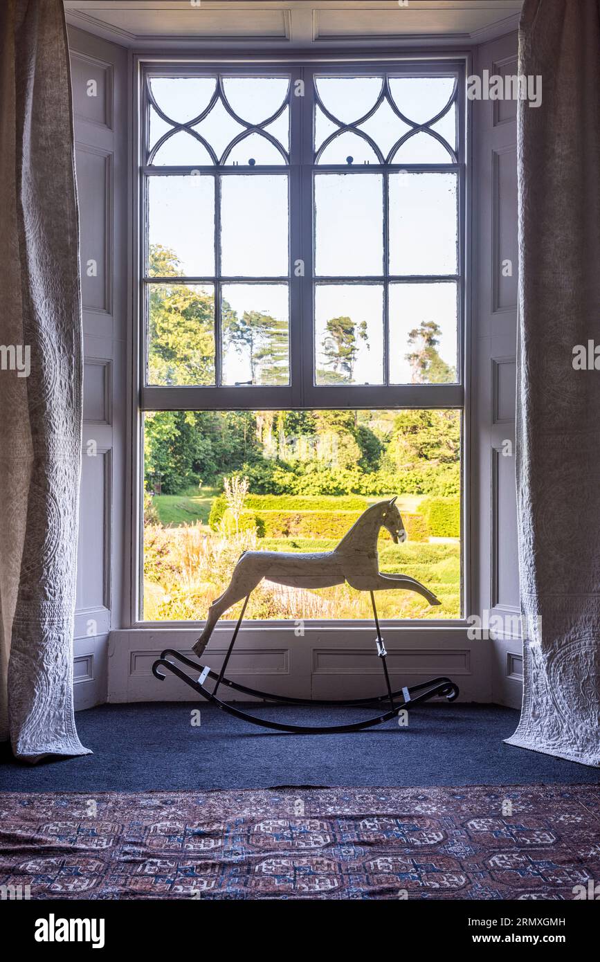 Cheval à bascule dans la fenêtre ouverte de la conversion de loft de fleurs du 18e siècle près de Penzance en Cornouailles, Royaume-Uni Banque D'Images