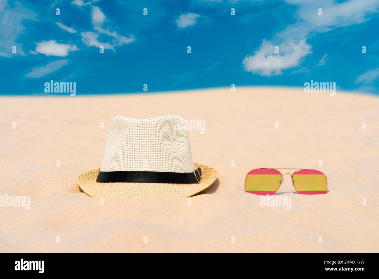 Lunettes de soleil avec des lunettes en forme de drapeau de l'Espagne et un chapeau reposent sur le sable contre le ciel bleu. Concept de vacances d'été et de voyage en Espagne. Repos estival Banque D'Images