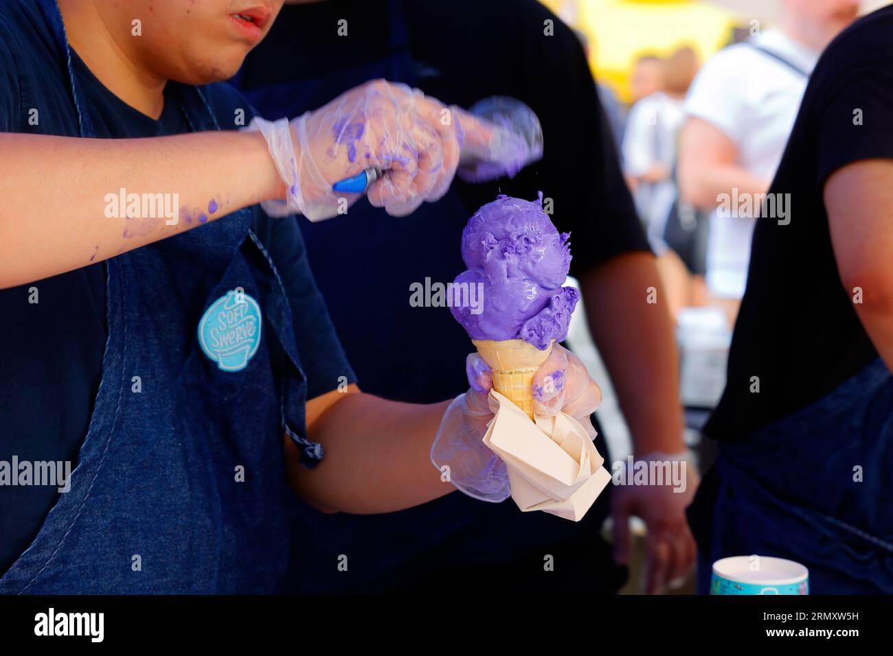 Un travailleur de Soft Swerve ramasse une double boule de crème glacée ube sur un cône de gaufrette à une foire de rue du festival alimentaire des Philippines Fest à New York, le 27 août 2023. Banque D'Images