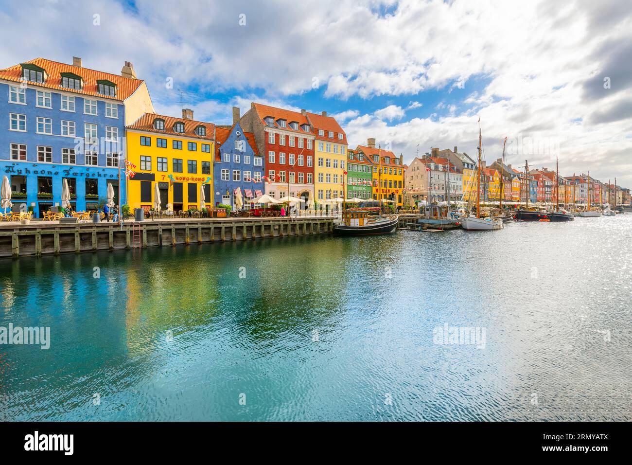 Bâtiments colorés avec des appartements, et des boutiques le long des terrasses de cafés et des voiliers amarrés au canal Nyhavn du 17e siècle. Banque D'Images