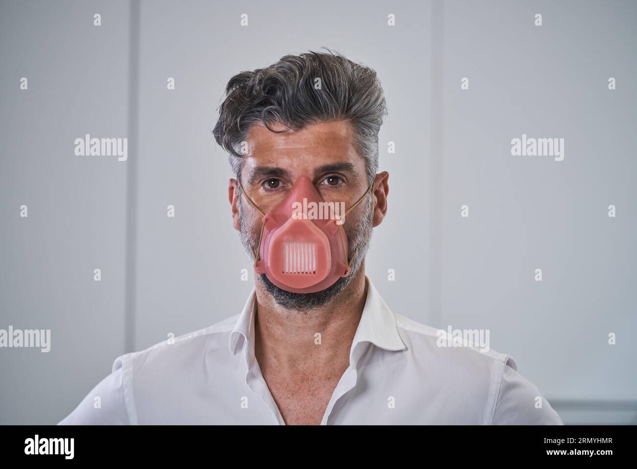 Portrait d'un homme en chemise blanche portant un respirateur et empêchant la propagation du coronavirus en suivant la restriction de quarantaine tout en se tenant debout sur un bac blanc Banque D'Images