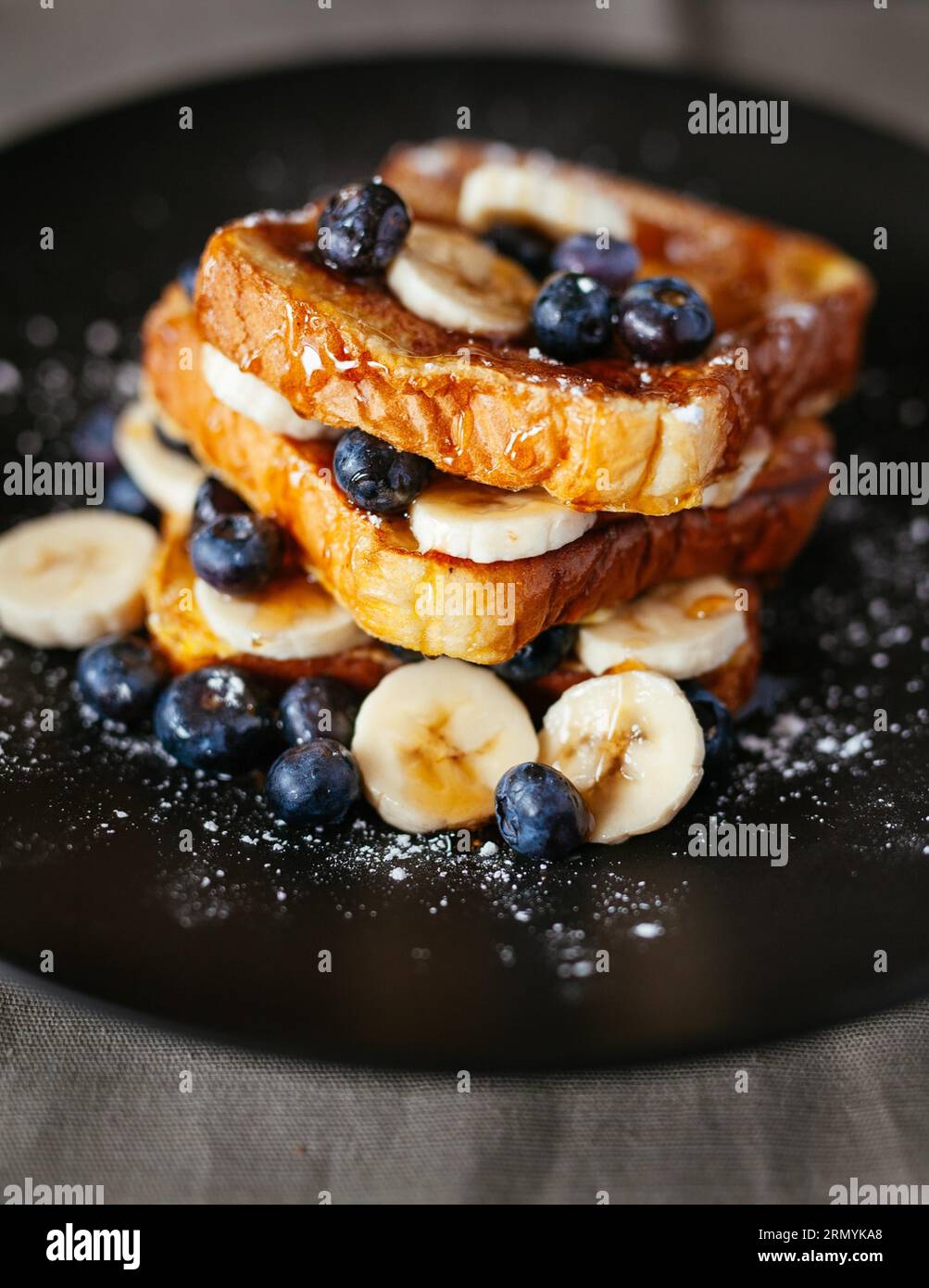 Image en gros plan d'une gaufre dorée garnie de bleuets frais et de bananes tranchées Banque D'Images
