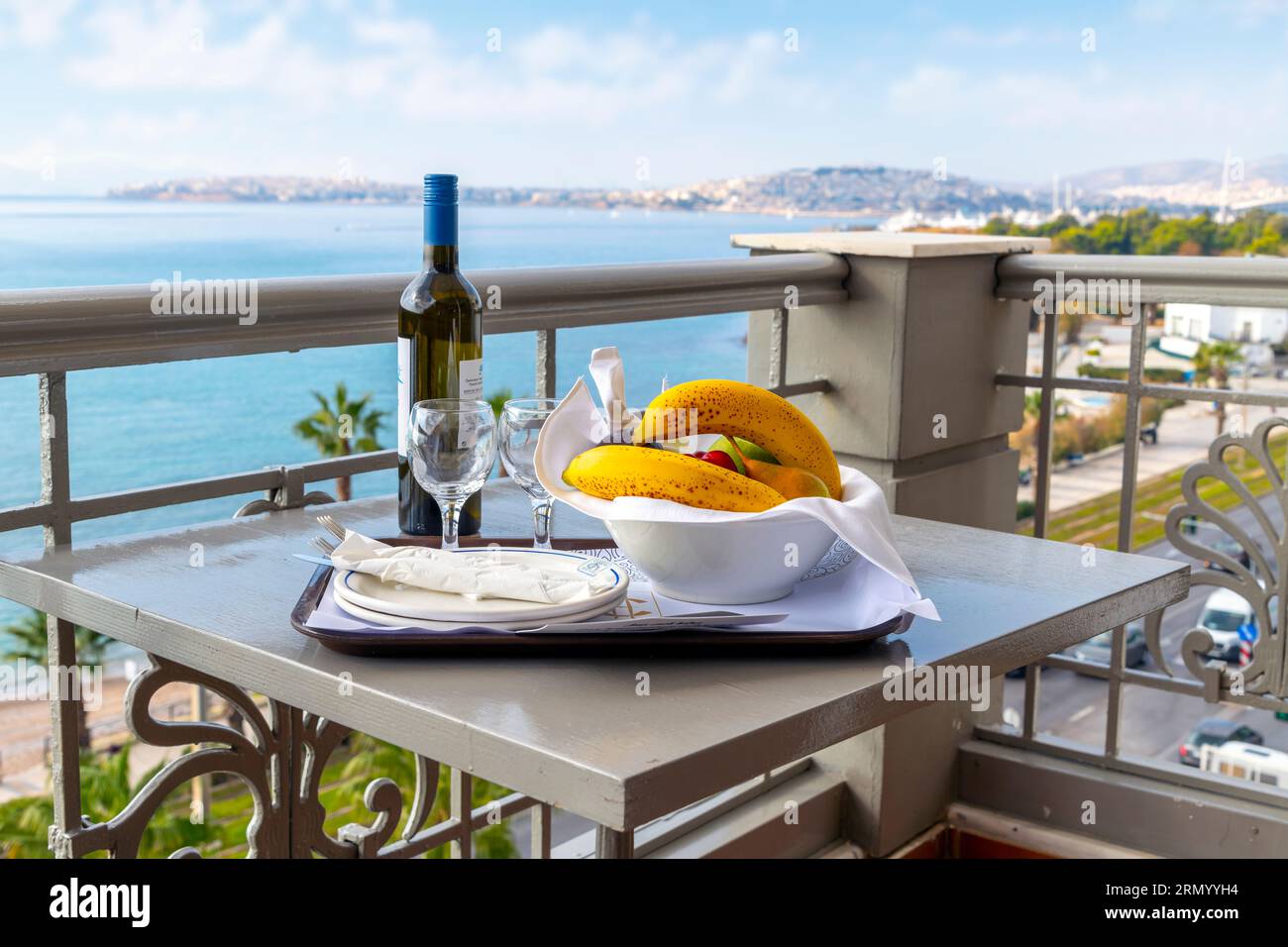 Vue depuis le balcon d'un hôtel d'une bouteille de vin, deux verres de vin et un bol de fruits, le long de la Riviera athénienne près du Pirée à Palaio Faliro, Grèce. Banque D'Images