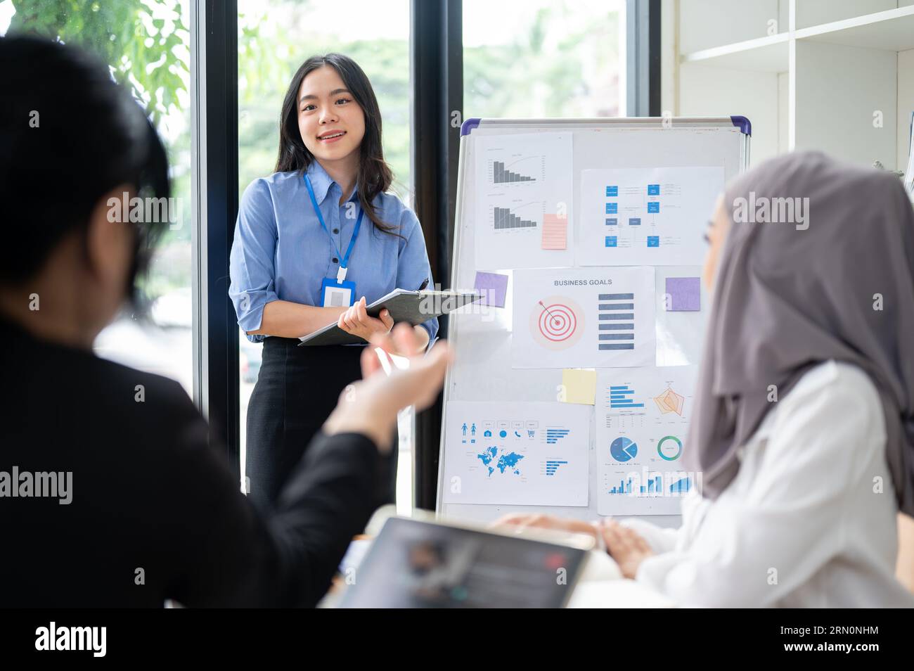 Une jeune femme d'affaires asiatique confiante et charmante ou une assistante marketing répond à une question de son équipe lors de sa présentation dans le Banque D'Images