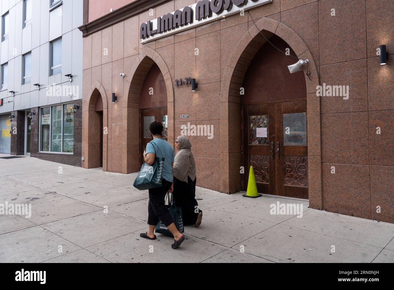 New York, États-Unis. 29 août 2023. Les gens marchent près de la mosquée Al-Iman dans le quartier Astoria de Queens Borough de New York. Selon les nouvelles directives annoncées aujourd'hui par le maire de New York, Eric Adams, les mosquées n'auront pas besoin d'un permis spécial pour diffuser publiquement l'appel islamique à la prière, ou adhan, le vendredi et au coucher du soleil pendant le mois sacré du Ramadan. Crédit : SOPA Images Limited/Alamy Live News Banque D'Images