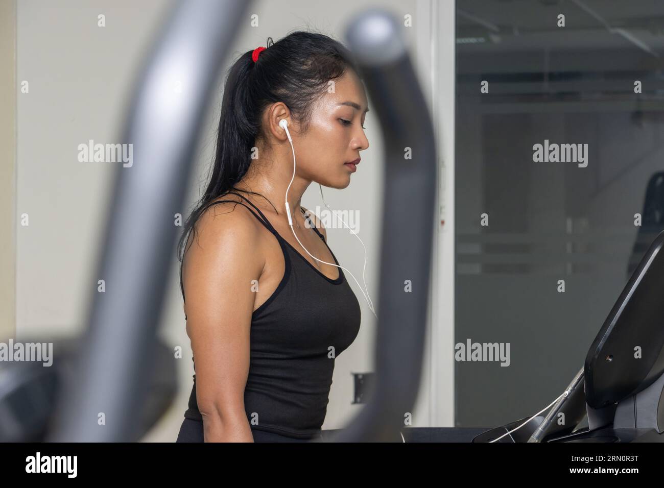 Femme en sueur utilise tapis roulant dans la salle de gym Banque D'Images