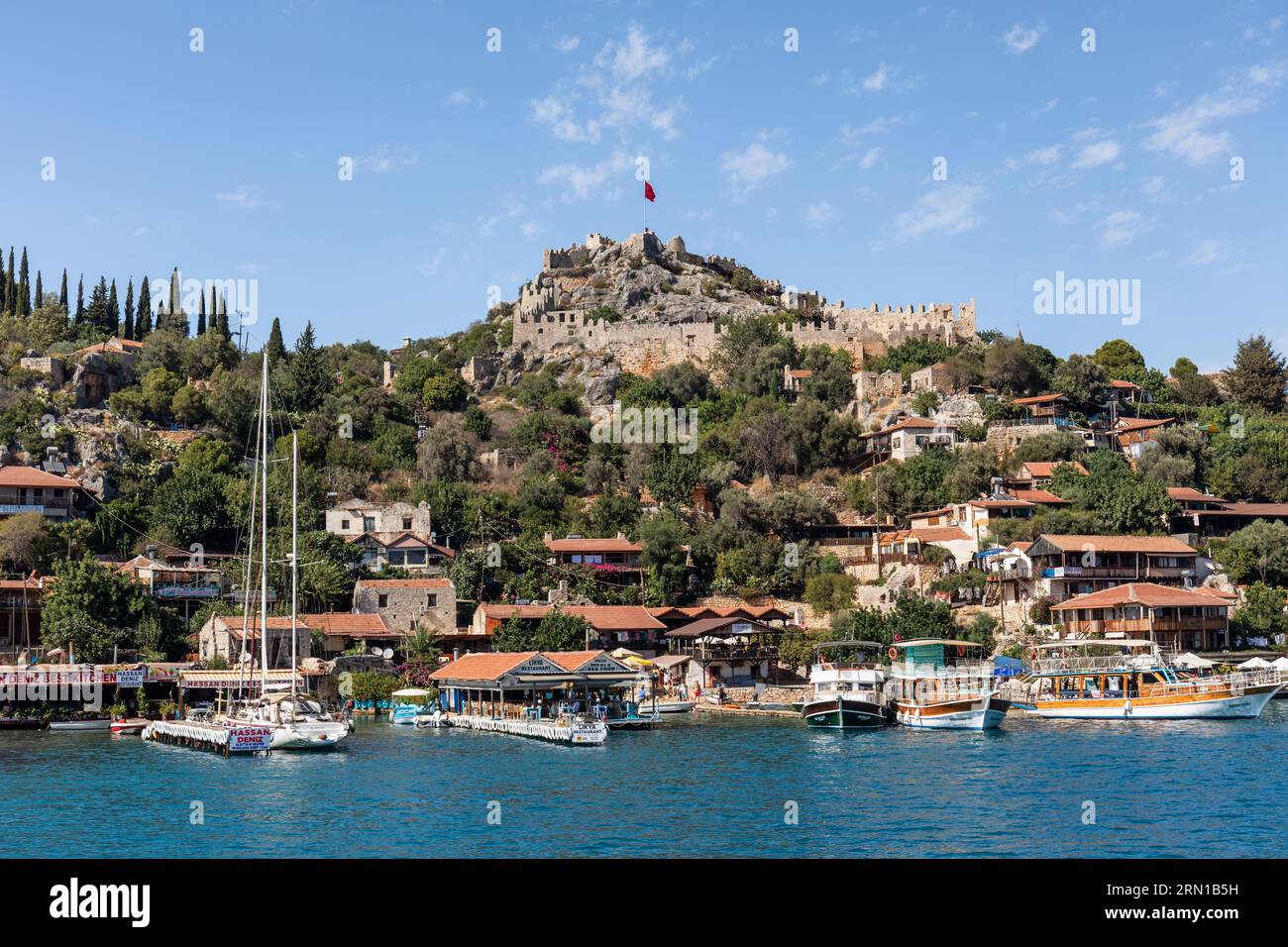 Village et château de Simena vu d'un bateau touristique arrivant, Simena, Kalekoy, Turquie Banque D'Images