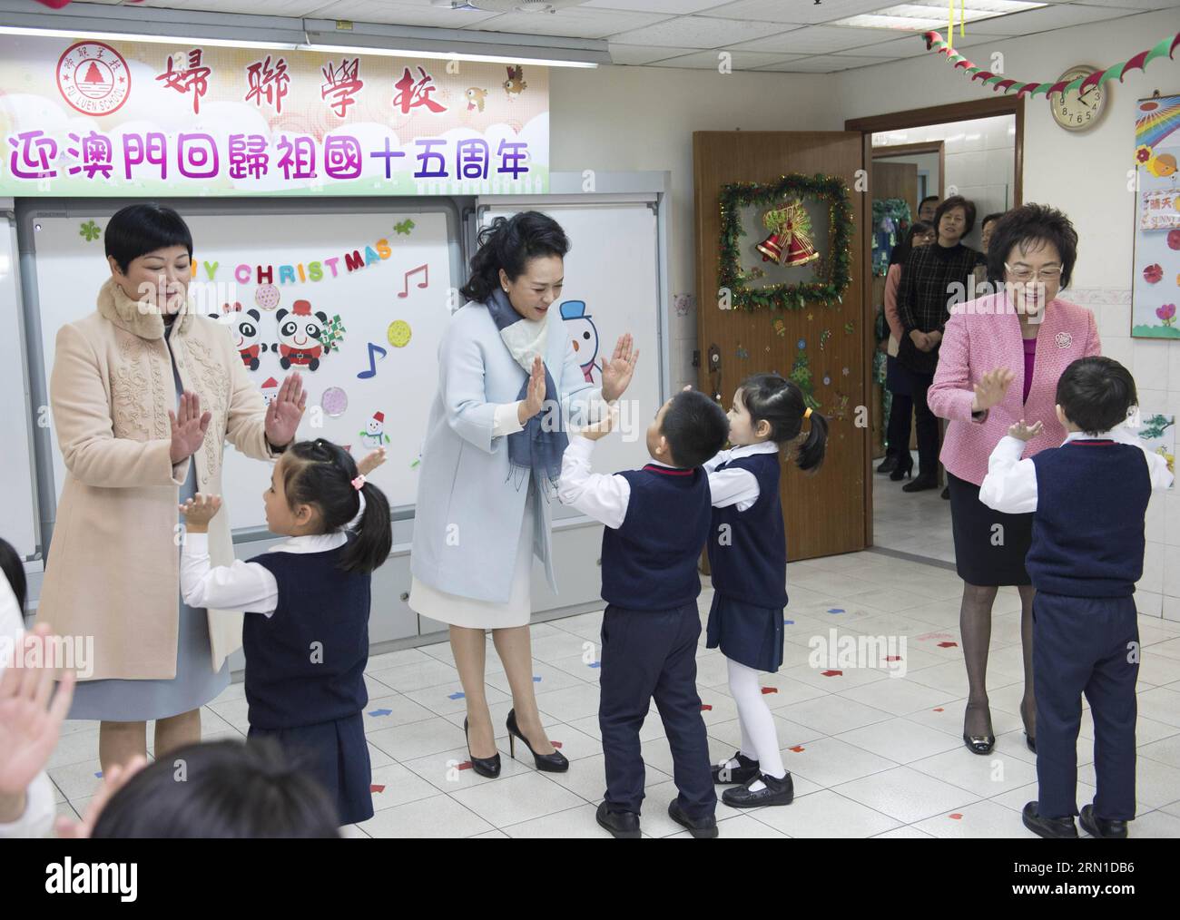 (141219) -- MACAO, 19 décembre 2014 -- Peng Liyuan (C), épouse du président chinois Xi Jinping, cinq ans avec deux enfants qui écoutent une rime folklorique lors de sa visite à un jardin d enfants de l Association générale des femmes de Macao en compagnie de Fok Wai Fun (L), épouse du chef de l exécutif de Macao, Chui Sai On, dans le sud de la Chine, Macao, 19 décembre 2014. ) (lmm) CHINA-MACAO-PENG LIYUAN-KINDERGARTEN-VISIT (CN) WangxYe PUBLICATIONxNOTxINxCHN Macao DEC 19 2014 Peng Liyuan C épouse du président chinois Xi Jinping High Fives avec deux enfants comme ils listent à une rime folklorique lors de sa visite à un Kinderg Banque D'Images