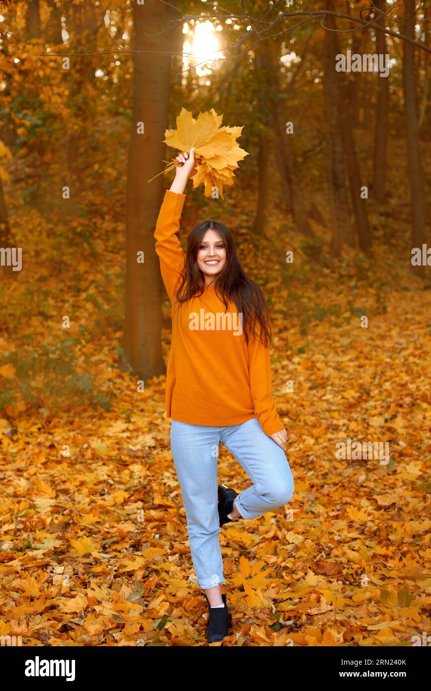 femme habillée de couleurs vives marchant dans la nature et heureux avec l'atmosphère automne tombant des feuilles Banque D'Images