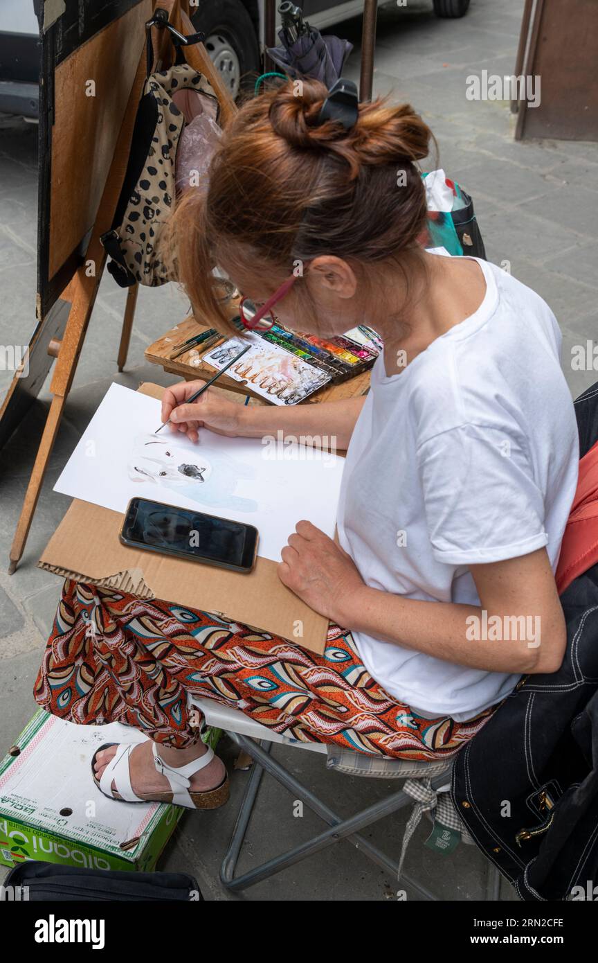 Une artiste peignant et vendant ses œuvres aux touristes en visite dans le Loggiato, une cour semi-fermée qui fait partie de la Galleria degli Uffizi Banque D'Images