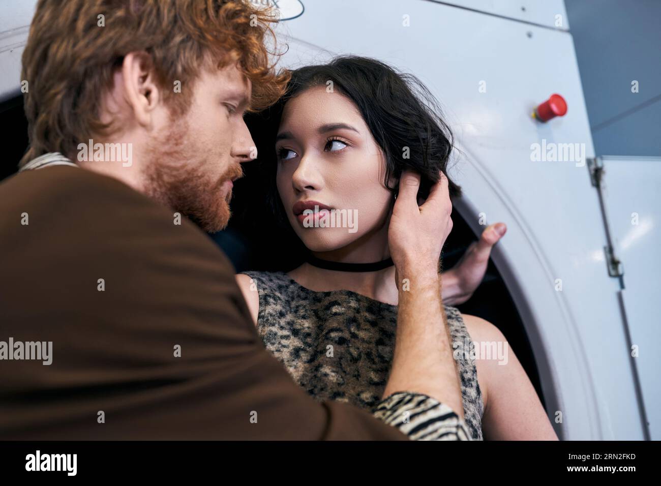 élégant jeune homme rousse touchant brune petite amie asiatique dans la blanchisserie publique Banque D'Images