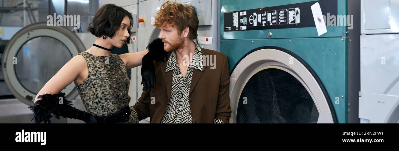 élégante jeune femme asiatique posant près de petit ami et machine à laver dans la blanchisserie publique, bannière Banque D'Images