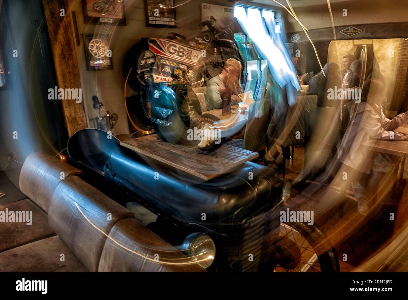 Image de vitesse d'obturation lente de l'intérieur d'un restaurant d'amateurs de moteur avec des véhicules et des personnes. Technique in camera. Angleterre Royaume-Uni Banque D'Images