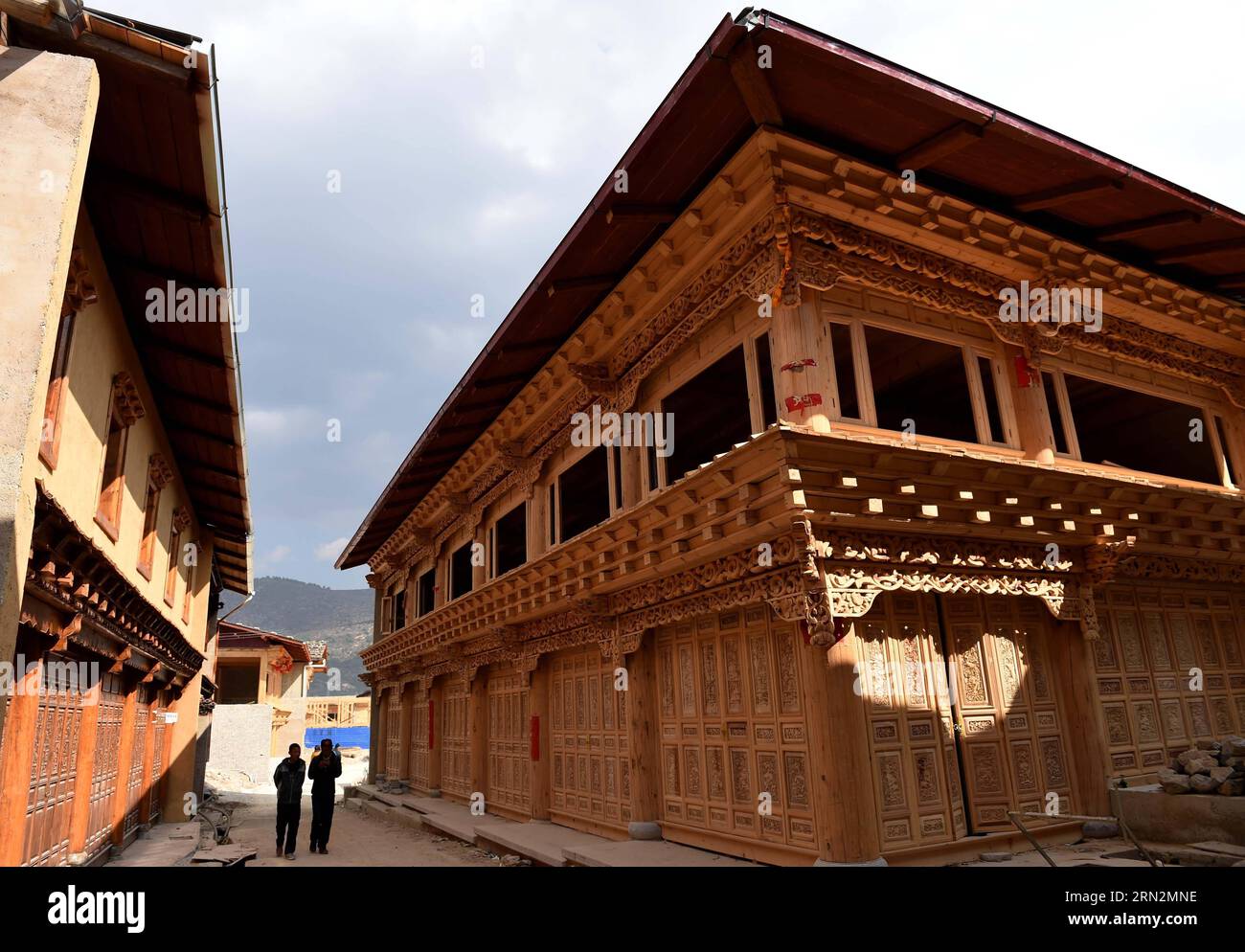 (150316) -- SHANGRI-LA, 16 mars 2015 -- les gens passent devant les maisons reconstruites de style tibétain dans l'ancienne ville de Dukezong dans le comté de Shangri-la, province du Yunnan au sud-ouest de la Chine, 14 mars 2015. Le projet général de restauration de l'ancienne ville de Dukezong qui a pris feu en janvier 2014 est bien avancé. L’ensemble du projet, d’une valeur de 1,2 milliards de yuans (196 millions de dollars américains), devrait être terminé en 2016. Dukezong, à l'est il y a plus de 1 300 ans, est connu pour ses architectures de style tibétain. L'incendie qui a éclaté en janvier 2014 a brûlé près d'un cinquième de Banque D'Images