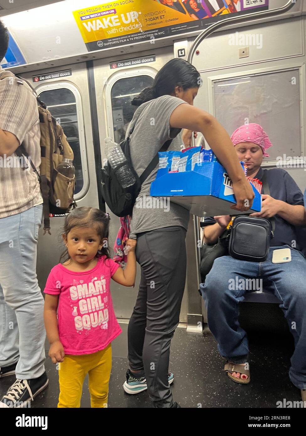 Une immigrante hispanique vend des bonbons dans un train de métro de New York avec sa jeune fille à Brooklyn, New York. Banque D'Images