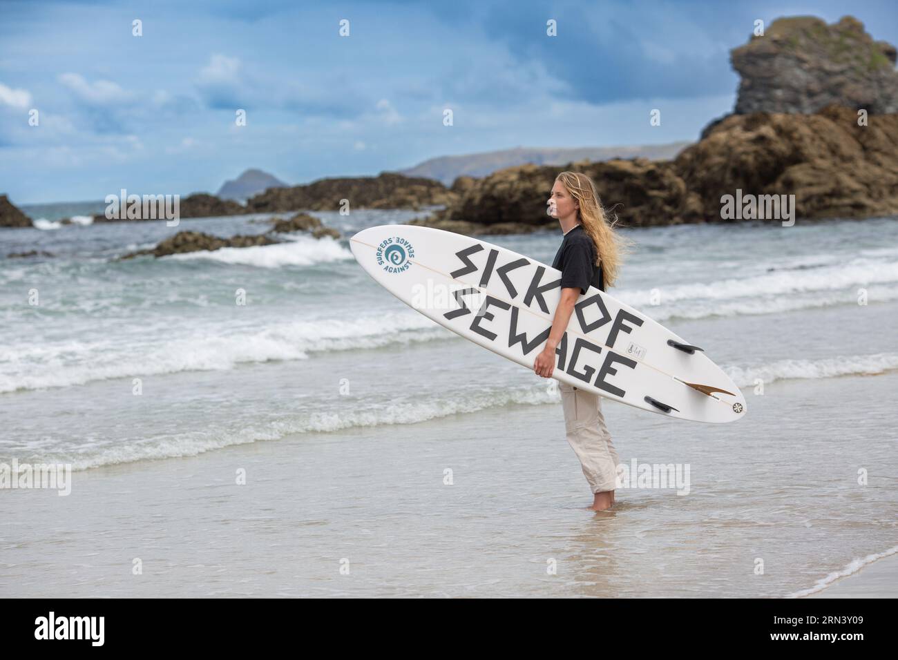 Trevaunance Cove , St Agnes , Cornouailles, Royaume-Uni , 21/07/2023 surfer contre les eaux usées Tabitha McCormick planche de surf avec un slogan "MALADE DES EAUX USÉES" . Banque D'Images