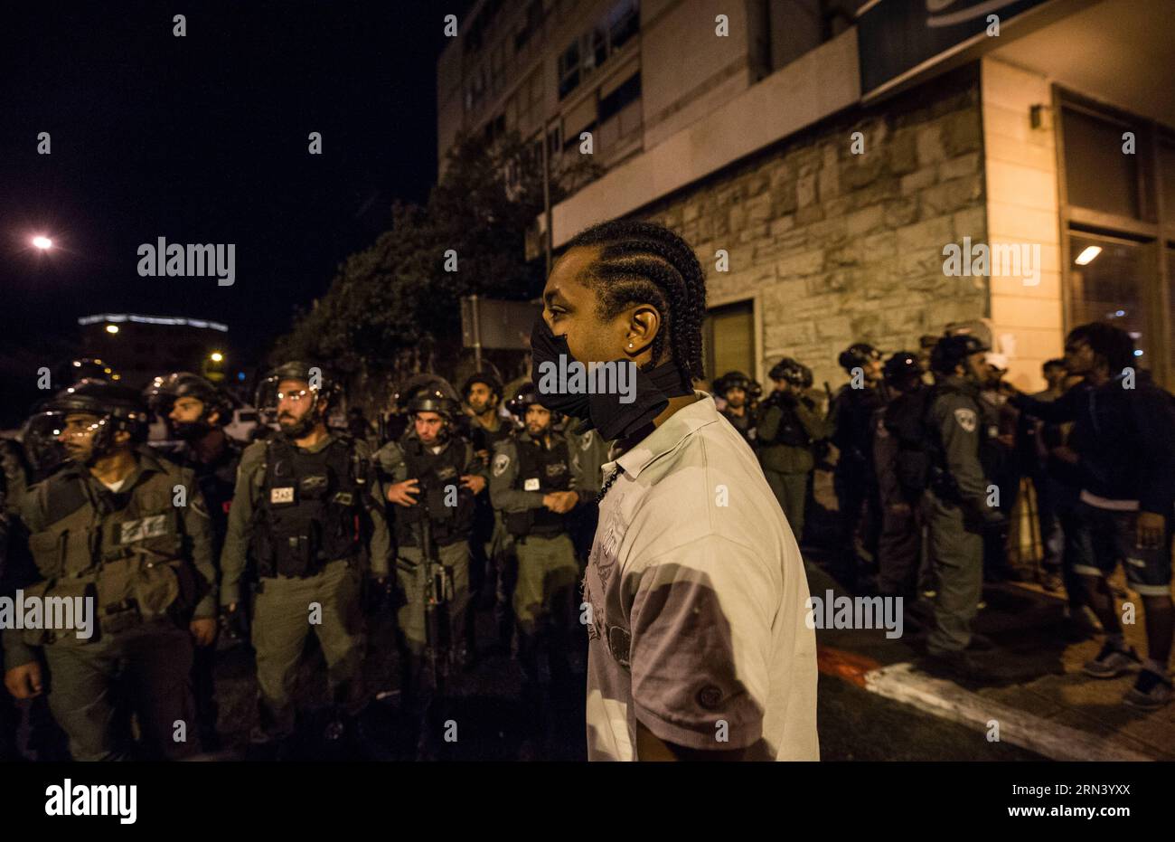 Un manifestant affronte des policiers israéliens lors d’une manifestation dans le centre de Jérusalem, le 30 avril 2015. Environ 1 000 Éthiopiens israéliens sont descendus dans les rues du centre de Jérusalem jeudi soir pour protester contre la brutalité policière et le racisme, et se sont affrontés avec les forces de police. Les manifestants ont marché vers la place de Paris dans la ville, bloquant la circulation. Ils ont lancé des pierres et des bouteilles de verre aux forces de sécurité qui ont essayé de les disperser avec des grenades assourdissantes et des gaz lacrymogènes. Les manifestants ont ensuite tenté de poursuivre leur marche vers la résidence voisine du Premier ministre, mais ont été bloqués par des dizaines de policiers Banque D'Images