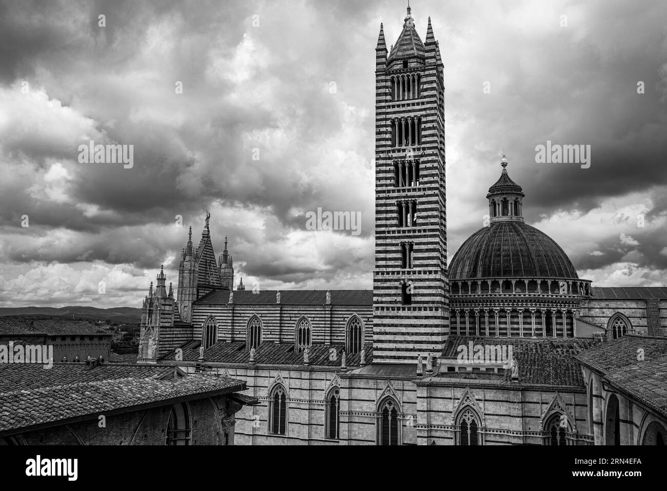 Nuages sombres sur la cathédrale de Sienne avec sa façade en marbre rayé noir et blanc, photo noir et blanc, Sienne, Toscane, Italie Banque D'Images