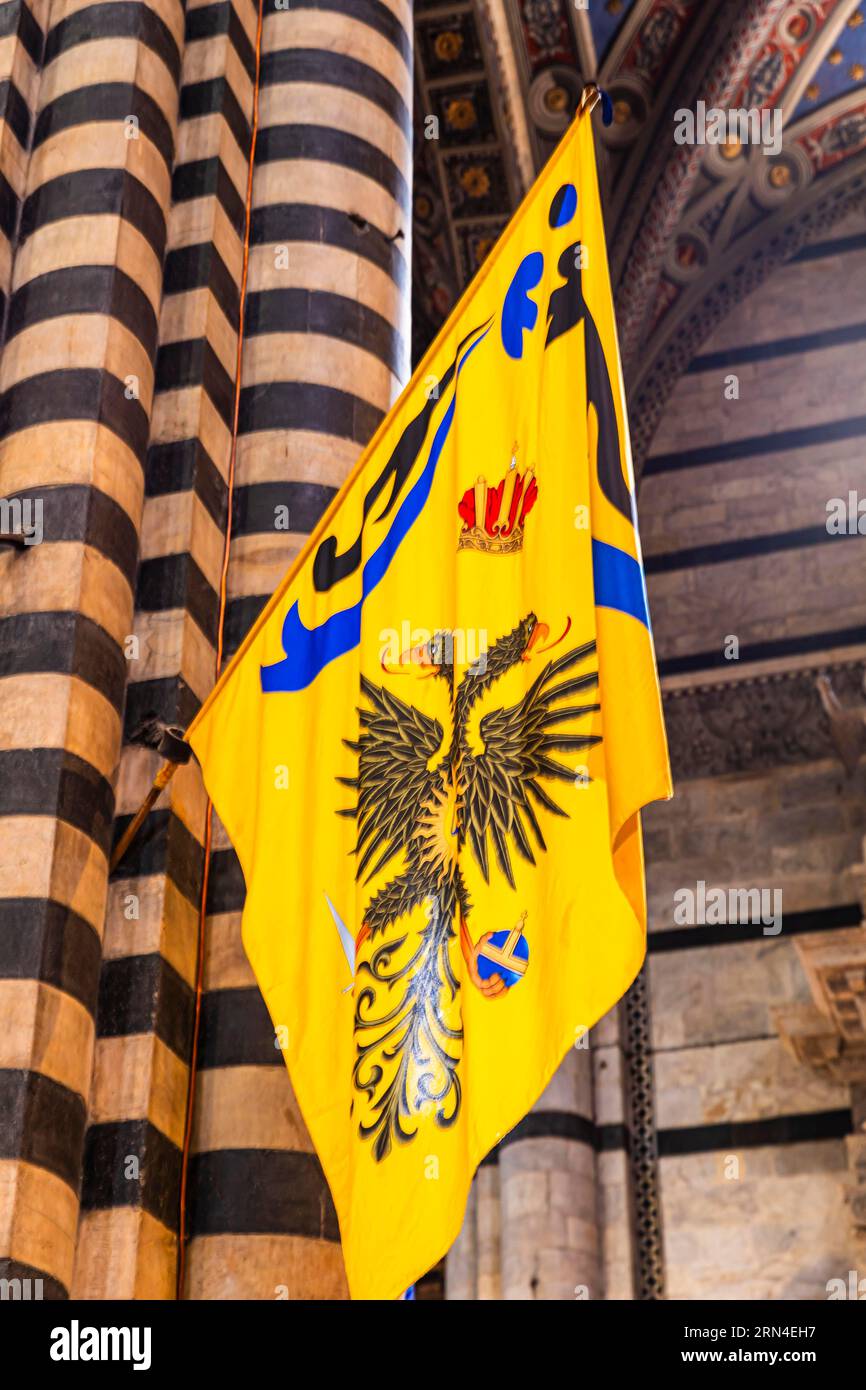 Colonne de marbre rayé noir et blanc de la cathédrale avec un drapeau Palio, Sienne, Toscane, Italie Banque D'Images