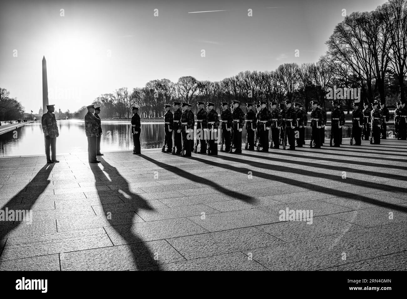 La garde d'honneur et le monument de Washington, Washington, DC photographie en noir et blanc montre la garde d'honneur debout en formation, avec de longues ombres projetées sur le sol. Banque D'Images