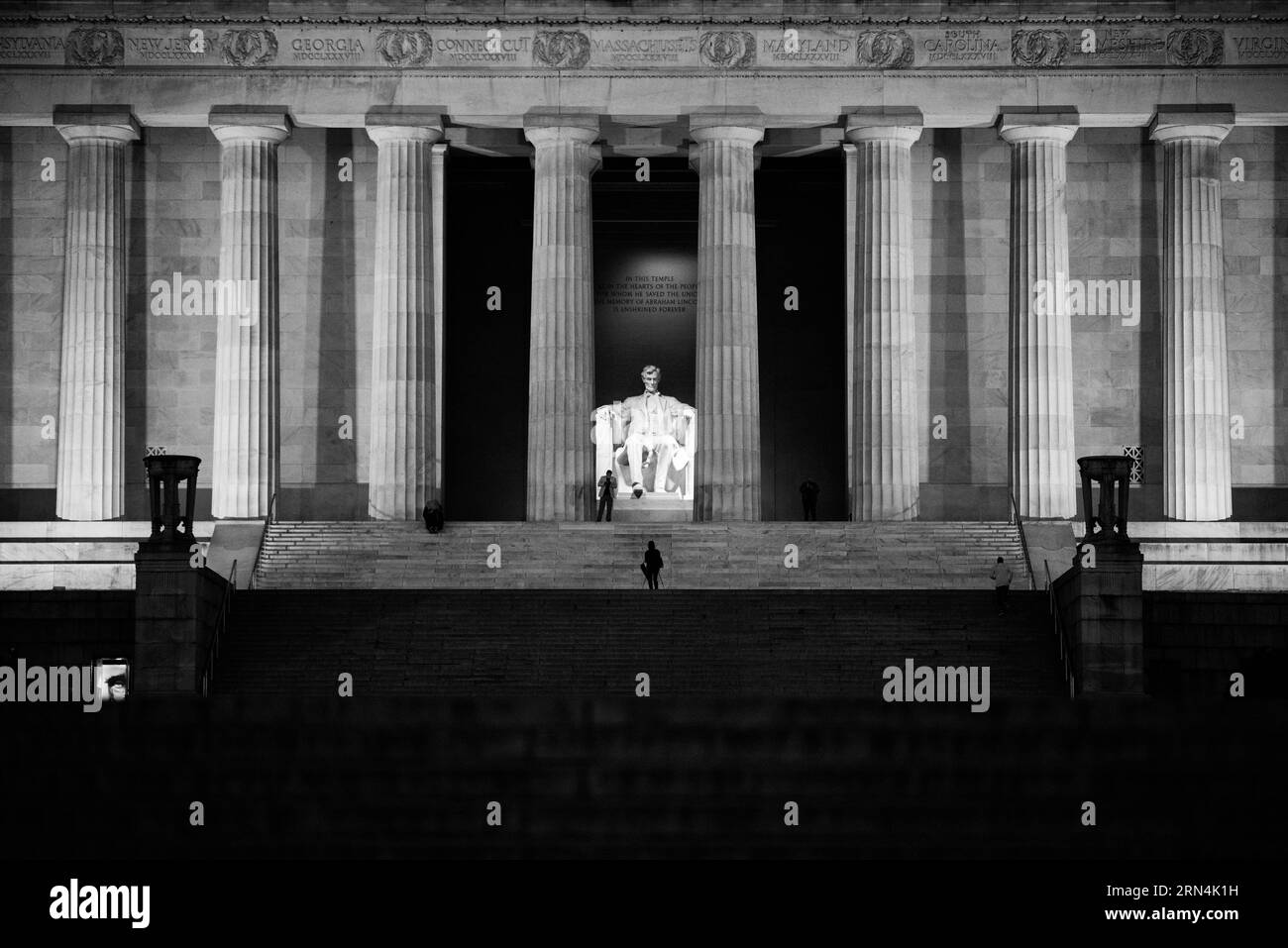 Façade du Lincoln Memorial, Washington DC — Photo noir et blanc | Lincoln Memorial de nuit, Washington, D.C. Photographie noir et blanc montrant la façade du monument avec des colonnes néoclassiques, la statue illuminée de Lincoln et des figures sur les marches. Banque D'Images