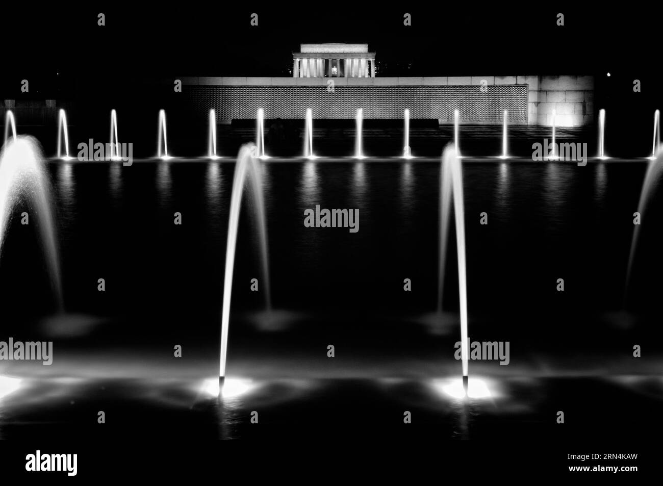 Fontaine commémorative de la seconde Guerre mondiale la nuit, National Mall, Washington DC photographie en noir et blanc montrant les jets de la fontaine et le Lincoln Memorial en arrière-plan. Banque D'Images