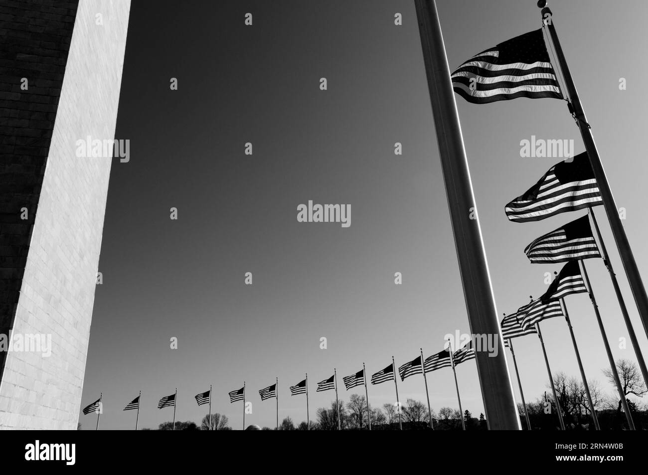 Drapeaux américains et Washington Monument, Washington DC — Photo noir et blanc | Washington Monument et drapeaux américains, Washington, D.C. Photographie noir et blanc montrant une vue en contre-plongée des drapeaux menant vers le monument contre un ciel clair. Banque D'Images