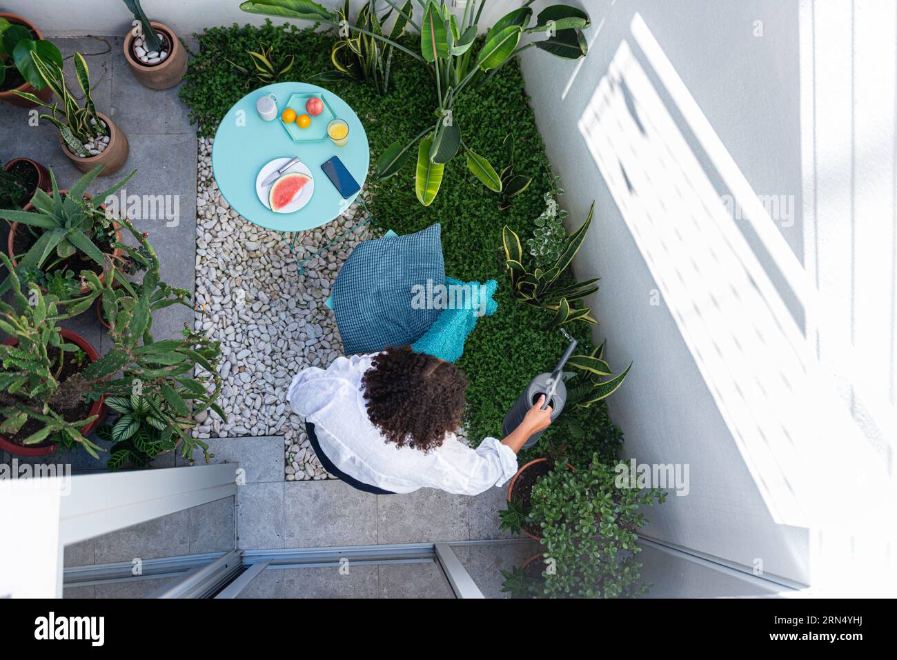 Femme arrosant des plantes dans son jardin intérieur Banque D'Images