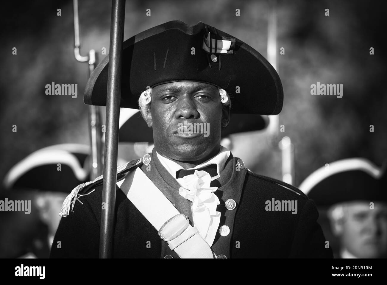 Soldat de la Old Guard, Joint Base Myer-Henderson Hall, Arlington, Virginie — Photo noir et blanc | Soldat de la Old Guard à la Joint Base Myer-Henderson Hall, Arlington. Photographie noir et blanc montrant le soldat en uniforme traditionnel, tenant un mousquet, avec d’autres soldats en arrière-plan. Banque D'Images