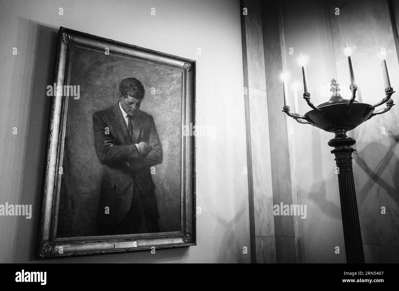 Portrait de John F Kennedy, Maison Blanche — Photo noir et blanc | Portrait de John F Kennedy, Maison Blanche. Photographie noir et blanc montrant la peinture encadrée du président les bras croisés, à côté d'un candélabre. Banque D'Images