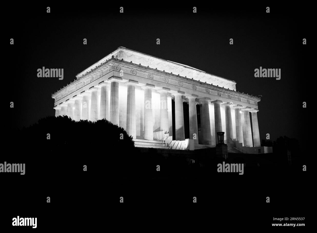 Lincoln Memorial la nuit, Washington DC — Photo noir et blanc | Lincoln Memorial la nuit, Washington, D.C. Photographie noir et blanc montrant le monument illuminé sur un ciel sombre, partiellement caché par des arbres. Banque D'Images