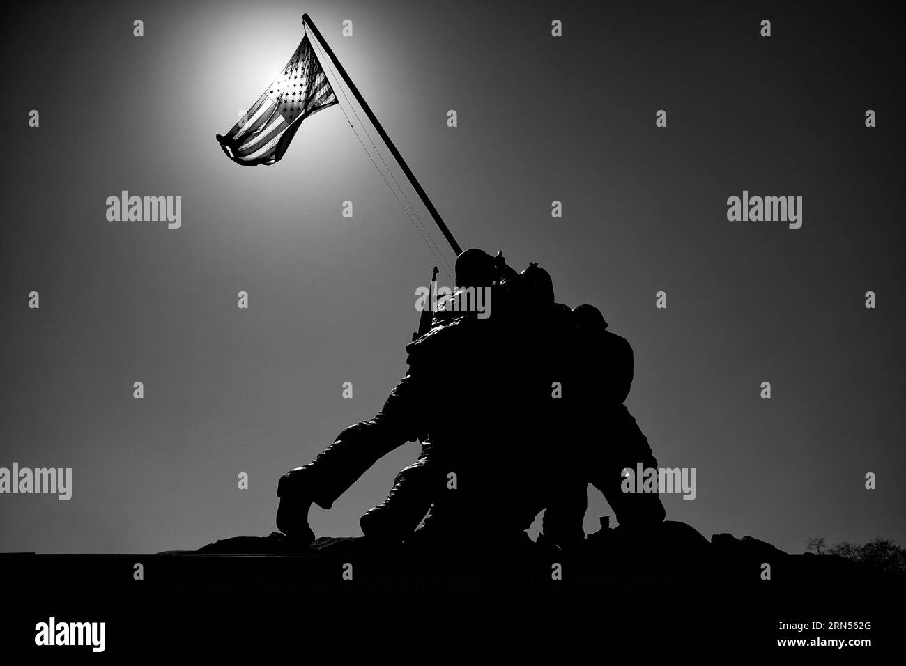 Mémorial d'Iwo Jima, Arlington, Virginie — Photo noir et blanc | Mémorial d'Iwo Jima, Arlington, Virginie. Une photographie noir et blanc montre le monument en silhouette devant un ciel lumineux, avec le drapeau américain flottant au-dessus. Banque D'Images