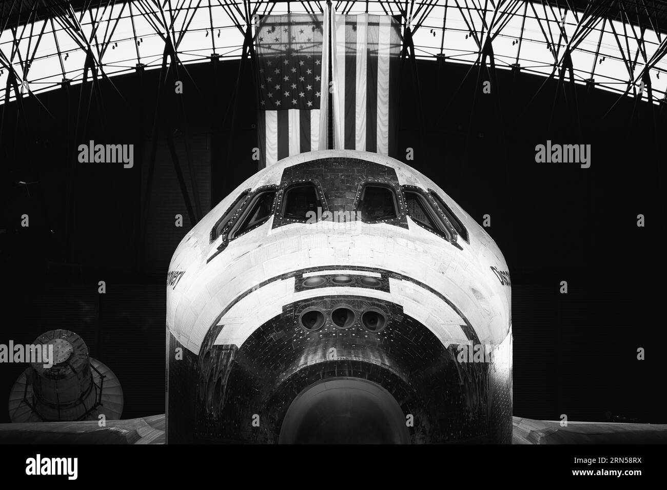 Navette spatiale Discovery. Photographie en noir et blanc du nez et du cockpit du vaisseau spatial, avec un drapeau américain en arrière-plan. Banque D'Images