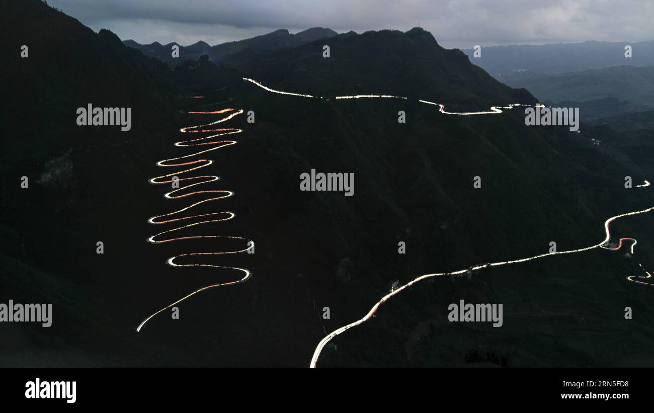 QINGLONG, le 24 juin 2015 -- cette photo à longue exposition prise par téléphone portable le 24 juin 2015 montre des traînées lumineuses de phares de voiture serpentant à travers un zigzag montagneux dans le comté de Qinglong, province du Guizhou au sud-ouest de la Chine. Le zigzag montagneux, également appelé 24-zig, qui est une section de la célèbre route de Stilwell, a vu plus de 2000 camions entièrement chargés de fournitures militaires passer chaque jour pendant la Seconde Guerre mondiale La route sinueuse de montagne a été terminée en 1935. En 1942, le corps du génie américain l'a rénové pour en faire une partie de la route Yunnan-Guizhou, une section de la route de Ledo, ou la route de Stilwell. Banque D'Images