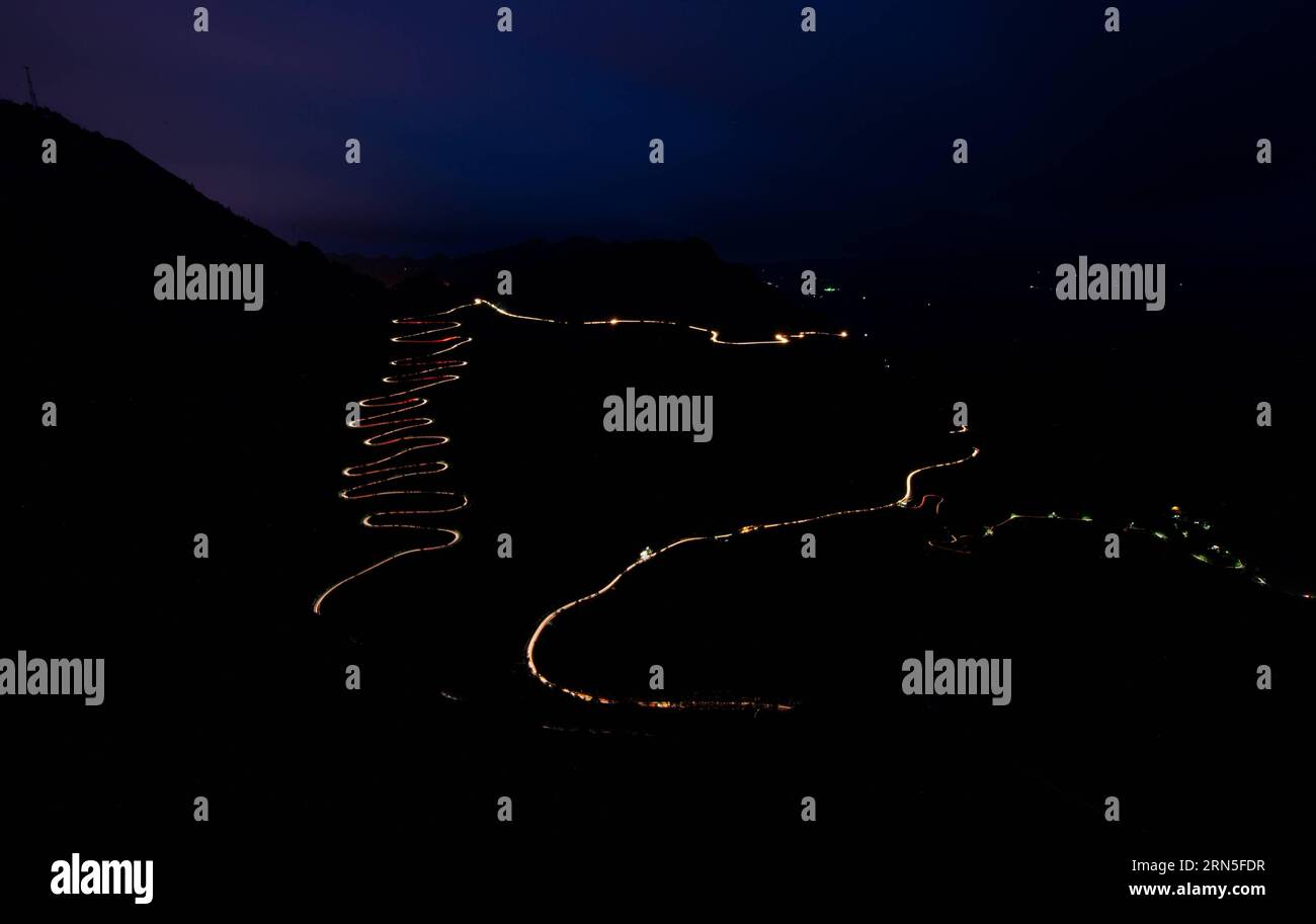 QINGLONG, le 24 juin 2015 -- cette photo à longue exposition prise par téléphone portable le 24 juin 2015 montre des traînées lumineuses de phares de voiture serpentant à travers un zigzag montagneux dans le comté de Qinglong, province du Guizhou au sud-ouest de la Chine. Le zigzag montagneux, également appelé 24-zig, qui est une section de la célèbre route de Stilwell, a vu plus de 2000 camions entièrement chargés de fournitures militaires passer chaque jour pendant la Seconde Guerre mondiale La route sinueuse de montagne a été terminée en 1935. En 1942, le corps du génie américain l'a rénové pour en faire une partie de la route Yunnan-Guizhou, une section de la route de Ledo, ou la route de Stilwell. Banque D'Images