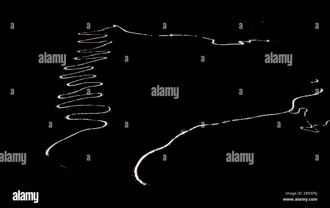 QINGLONG, le 24 juin 2015 -- cette photo à longue exposition prise par téléphone portable le 24 juin 2015 montre des traînées lumineuses de phares de voiture serpentant à travers un zigzag montagneux dans le comté de Qinglong, province du Guizhou au sud-ouest de la Chine. Le zigzag montagneux, également appelé 24-zig, qui est une section de la célèbre route de Stilwell, a vu plus de 2000 camions entièrement chargés de fournitures militaires passer chaque jour pendant la Seconde Guerre mondiale La route sinueuse de montagne a été terminée en 1935. En 1942, le corps du génie américain l'a rénové pour en faire une partie de la route Yunnan-Guizhou, une section de la route de Ledo, ou la route de Stilwell. Banque D'Images