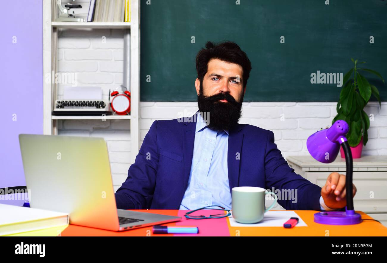 Lycée. Professeur d'université masculin travaillant avec un ordinateur portable dans la salle de classe. Journée des enseignants. Éducation, apprentissage, enseignement. Étudiant masculin souriant Banque D'Images