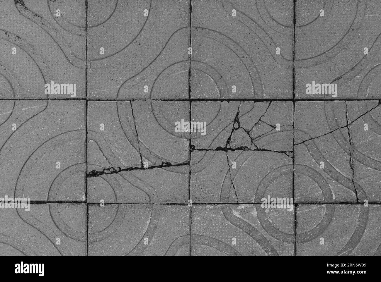 Pavés ou blocs carrés cassés et altérés avec des formes géométriques à l'extérieur, vus de dessus. Fond texturé en noir et blanc. Banque D'Images
