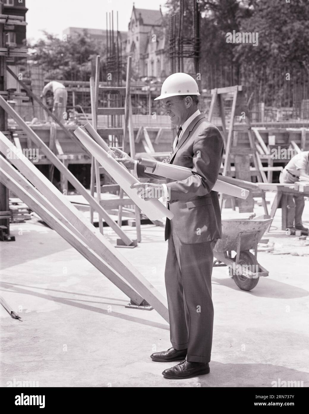 ARCHITECTE HOMME DES ANNÉES 1960 OU ENTREPRENEUR GÉNÉRAL DEBOUT SUR LE CHANTIER DE CONSTRUCTION TENANT DES PLANS DE SPÉCIFICATIONS DE PLAN PORTANT LE CASQUE DUR - S15572 HAR001 HARS ARCHITECTURE EMPLOIS SITE DIRECTEUR GÉNÉRAL PLANS COPIE ESPACE PLEINE LONGUEUR PERSONNES INSPIRATION HOMMES ARCHITECTES BÂTIMENTS PROFESSION CONFIANCE CADRES CONSTRUCTEUR MOYEN ÂGE B&W OBJECTIFS DE L'HOMME D'ÂGE MOYEN SUCCÈS COMPÉTENCE COMBINAISON ET CRAVATE RÊVES STRUCTURE D'OCCUPATION COMPÉTENCES PROTECTION DE LA PROPRIÉTÉ CARRIÈRE LEADERSHIP PROGRESS OPPORTUNITÉ DE TRAVAIL EMPLOI D'AUTORITÉ HARDHAT OCCUPATIONS DE PATRONS IMMOBILIERS STRUCTURES ÉLÉGANTES EDIFICE EMPLOYÉ OU GESTIONNAIRES DE CRÉATIVITÉ Banque D'Images