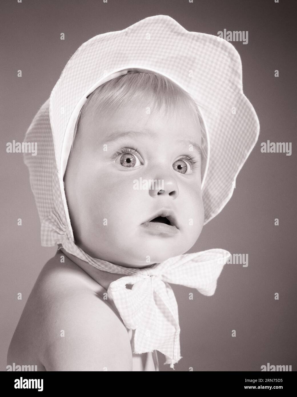 1960S BÉBÉ FILLE AVEC EXPRESSION FACIALE INCERTAINE PORTANT BONNET À CARREAUX ATTACHÉ EN ARC SOUS CHIN - B22612 HAR001 HARS ET VÉRIFIÉ HÉSITANT INCERTAIN ÉLÉGANT GRANDS YEUX DOUTEUX MODES CROISSANCE JEUNES FILLE NOIR ET BLANC CAUCASIEN ETHNICITÉ DOUTEUSE HAR001 INNOCENCE INNOCENT OLD FASHIONED INCERTAIN Banque D'Images