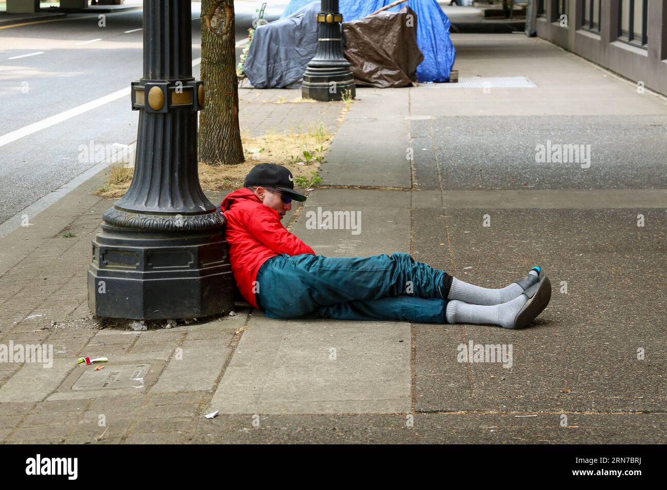 Personne sans-abri sous drogue se reposant sur le trottoir dans le centre-ville de Portland Oregon Banque D'Images