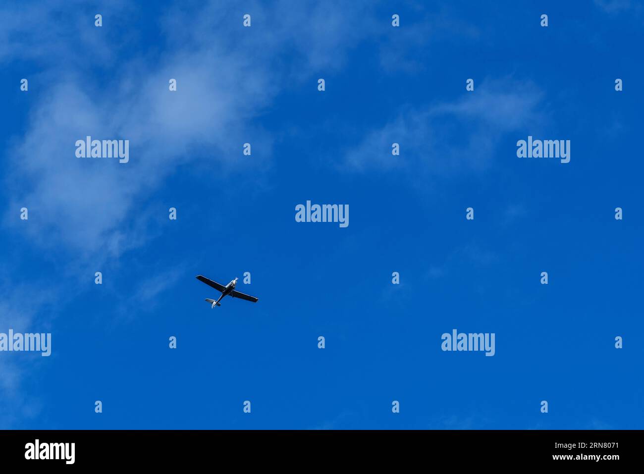 Petit avion blanc cessna monohélice volant dans un ciel bleu clair Banque D'Images