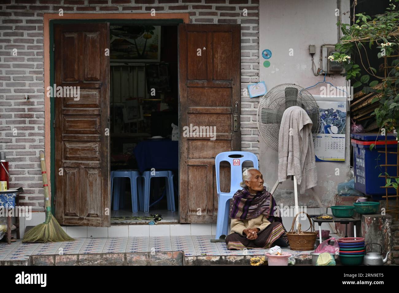 Vieille laotienne assise dans la rue près de sa maison à Luang Prabang, Laos Banque D'Images