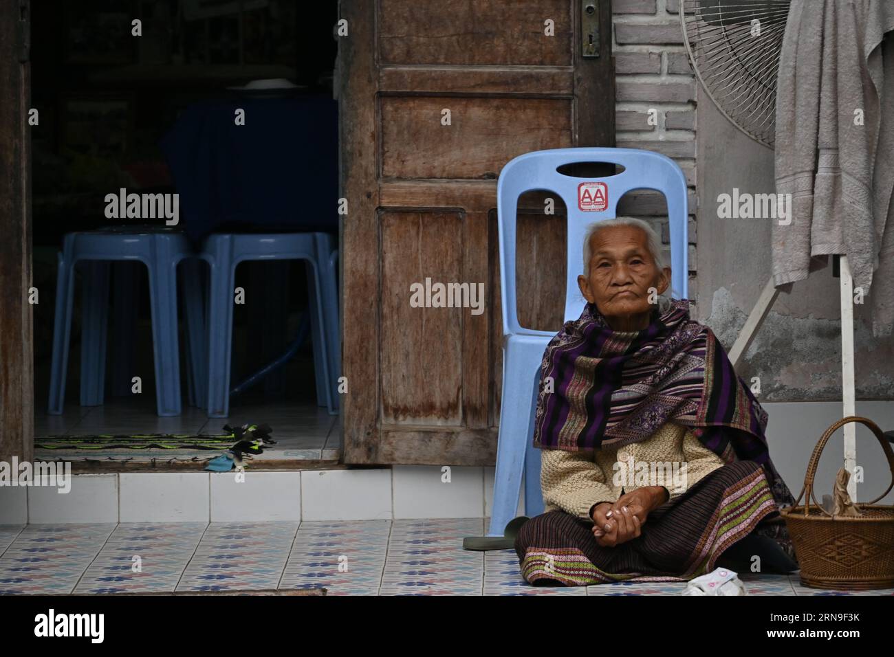 Vieille laotienne assise dans la rue près de sa maison à Luang Prabang, Laos Banque D'Images