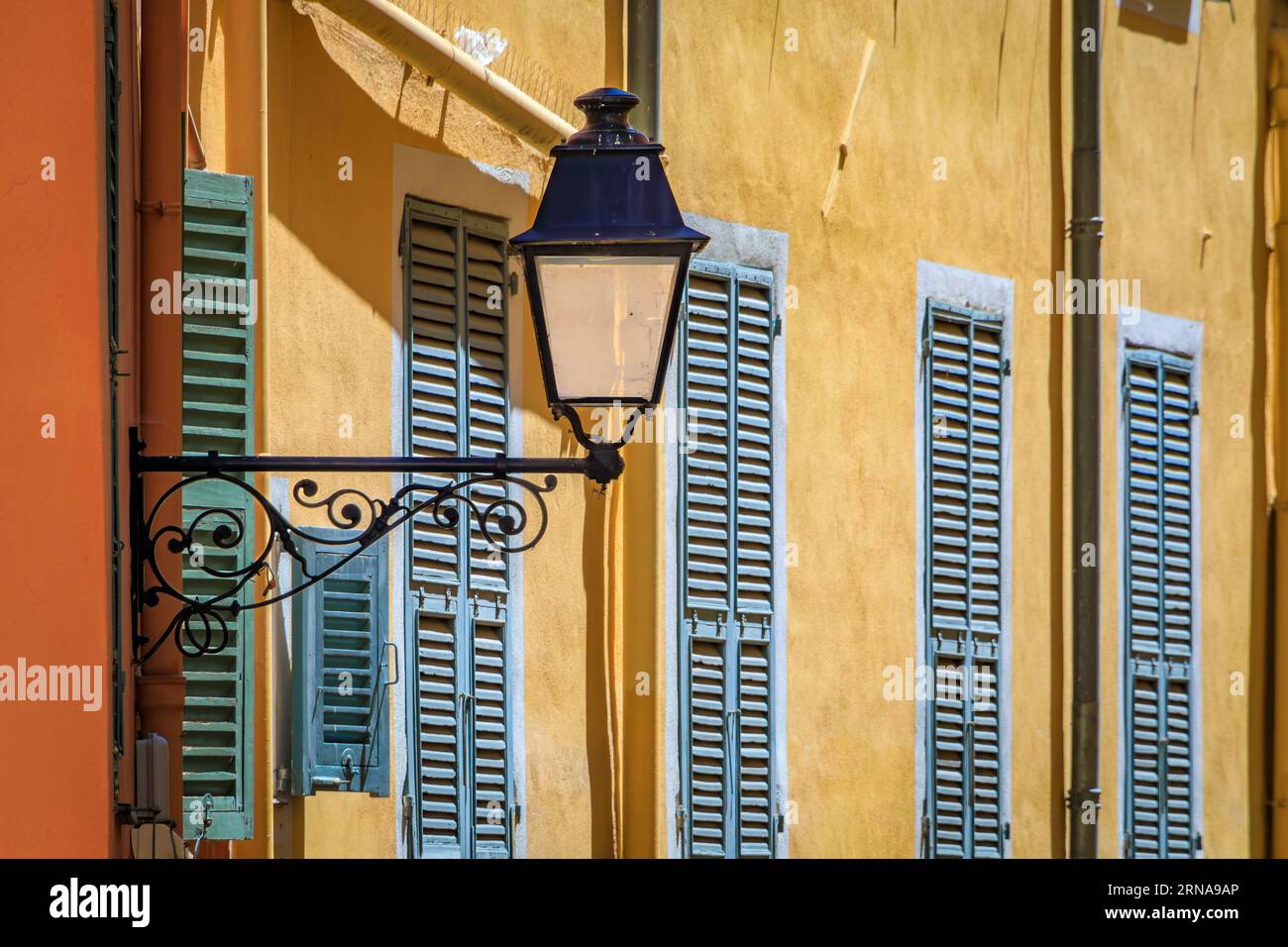 Pittoresque vieux lampadaire, maisons traditionnelles colorées avec volets en arrière-plan dans la vieille ville de Menton, Côte d'Azur, Sud de la France Banque D'Images