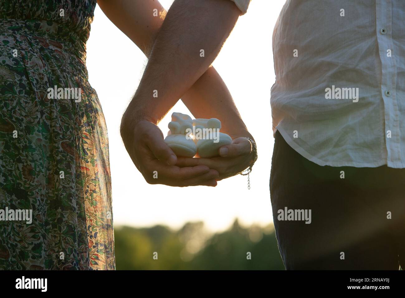 Image conceptuelle du genre révélant contre l'homophobie : couple attendant la naissance de leur fille avec bébé chaussures blanches à la main Banque D'Images