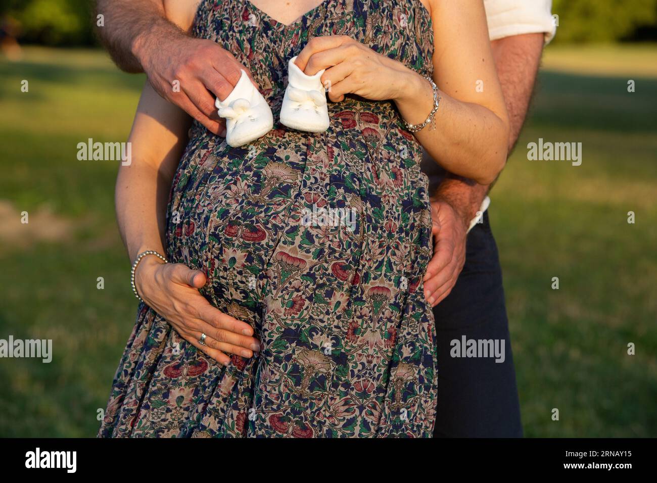 Image conceptuelle du genre révélant contre l'homophobie : couple attendant la naissance de leur fille avec bébé chaussures blanches à la main Banque D'Images